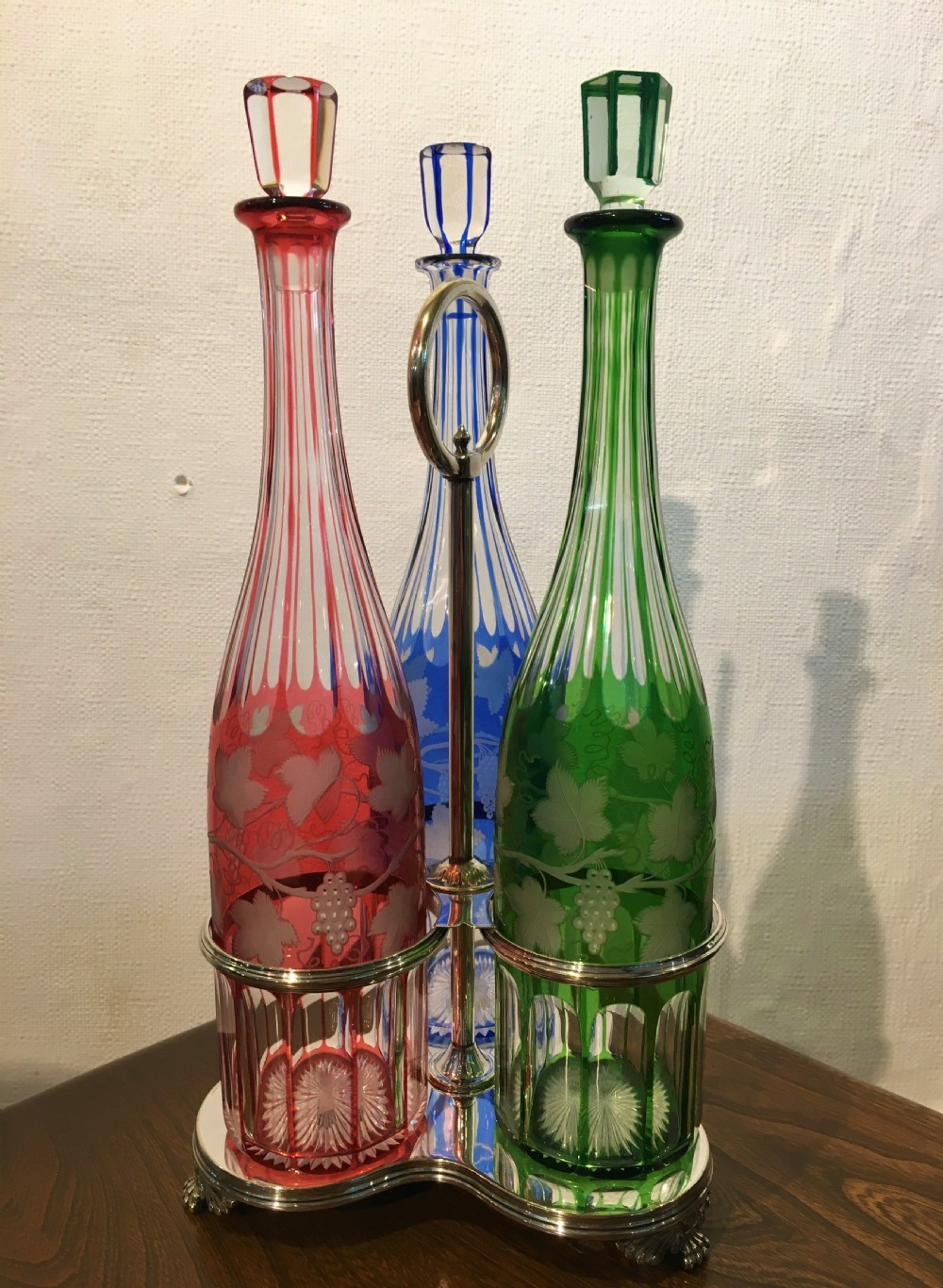 Three Coloured Tall Cut Vine & Grape Engraved Decanters in a Handled Stand c1840