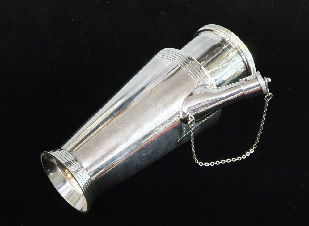 An Art Deco silver-plated cocktail shaker featuring a tapered conical body with turned concentric bands, an angular handle, and a spout with a chained cap stopper. View VIII