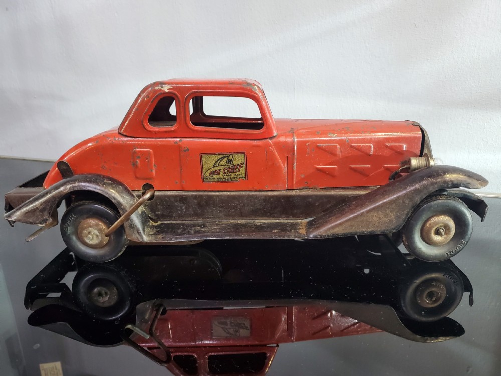 A 1930s red and black pressed steel Fire Chief toy coupe car with clockwork lever and original side decal.
