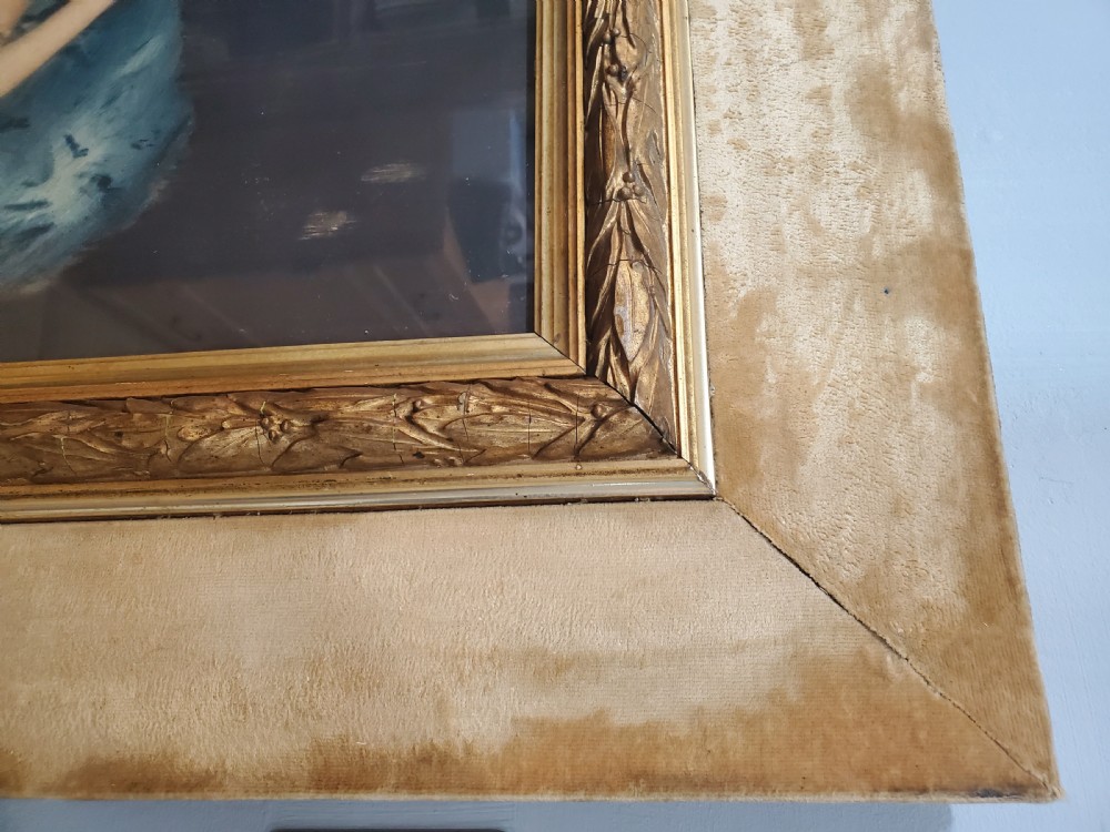 A large Art Deco framed portrait print depicting a seated woman in a patterned skirt, set inside a gold leaf inner moulding and a broad cream-painted outer frame. View V