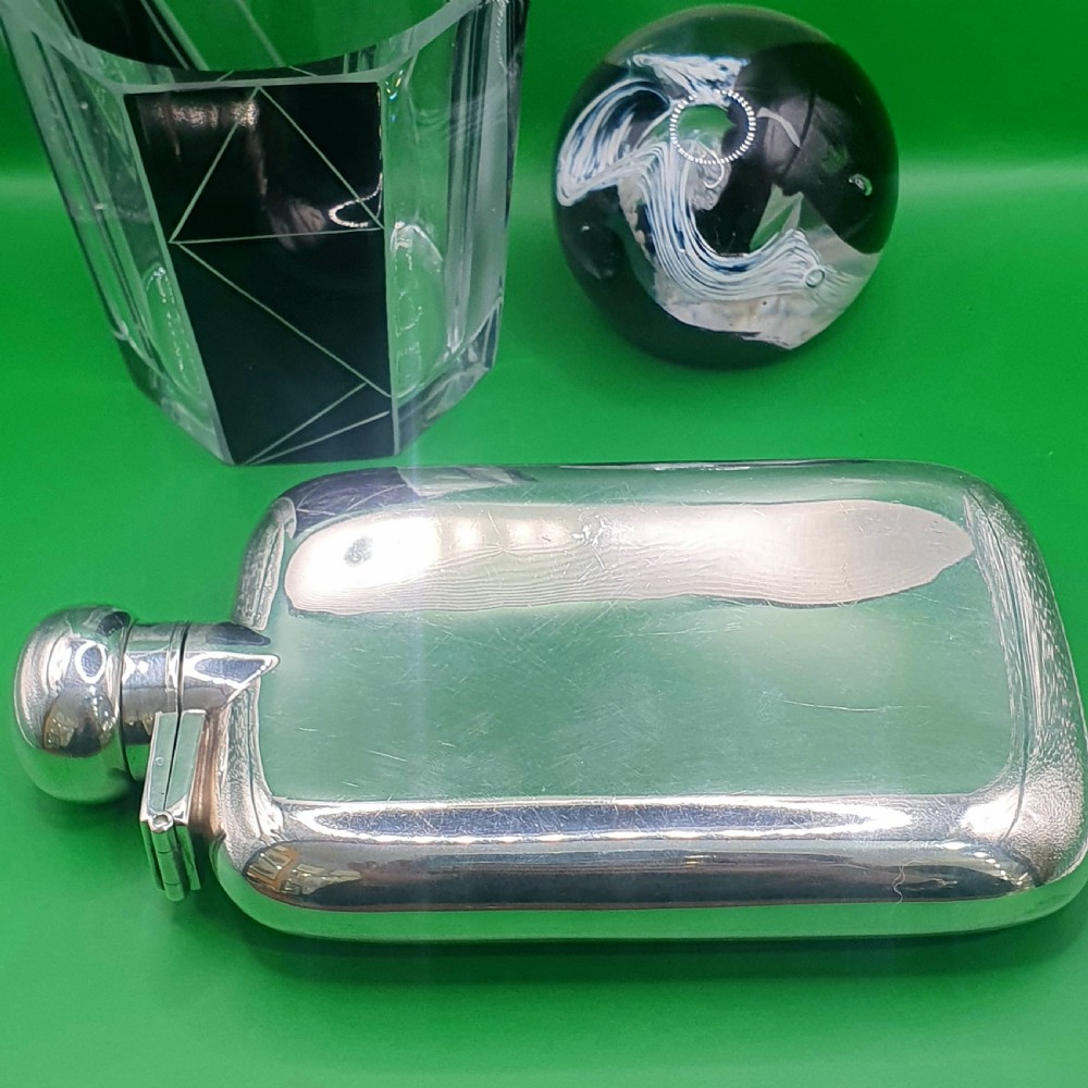 A polished sterling silver hip flask featuring a curved rectangular shape and a hinged bayonet top cap. View V