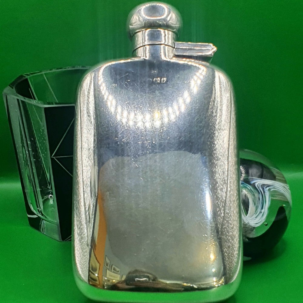 A polished sterling silver hip flask featuring a curved rectangular shape and a hinged bayonet top cap.