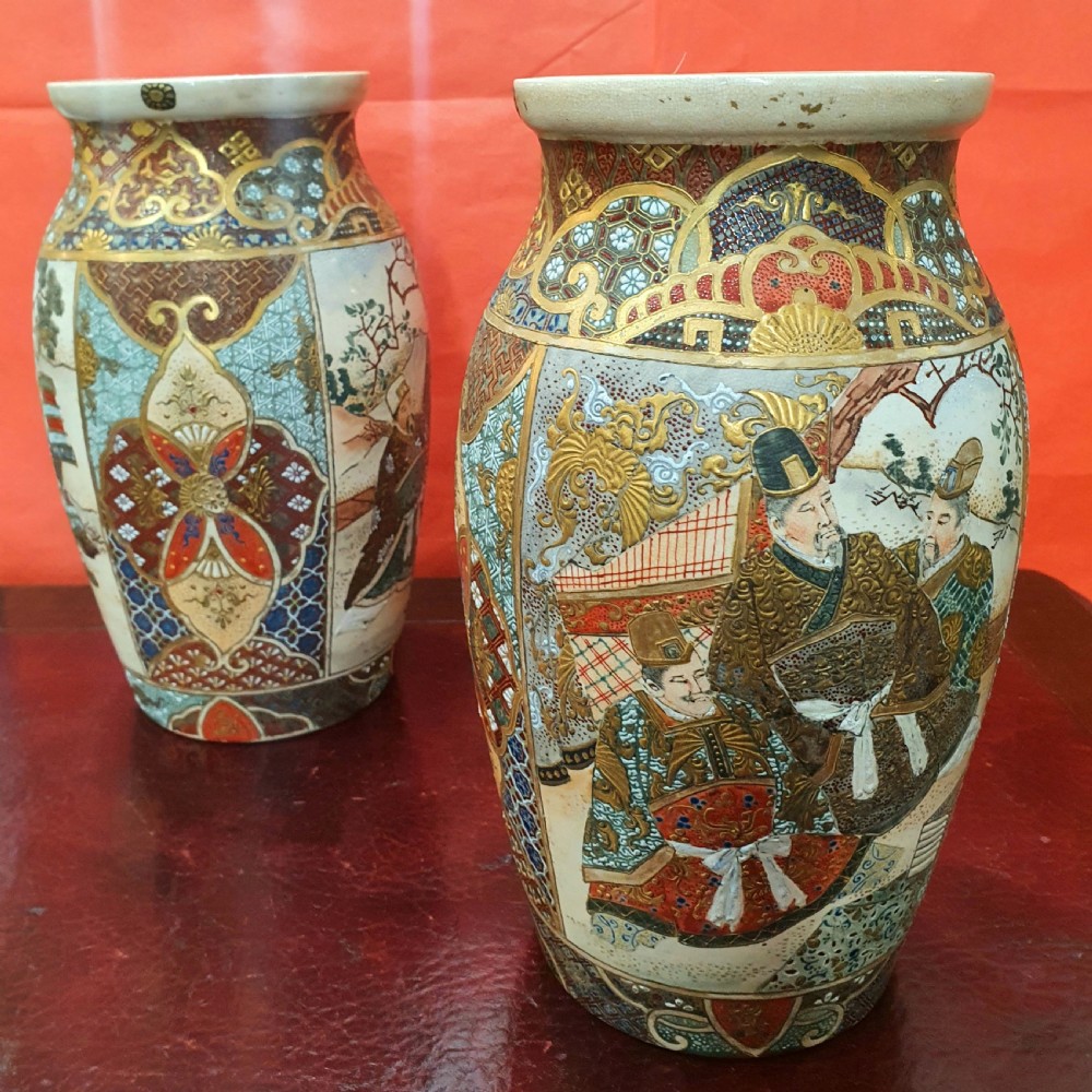 A pair of Japanese Satsuma earthenware vases decorated with detailed gilded panels and painted figures.