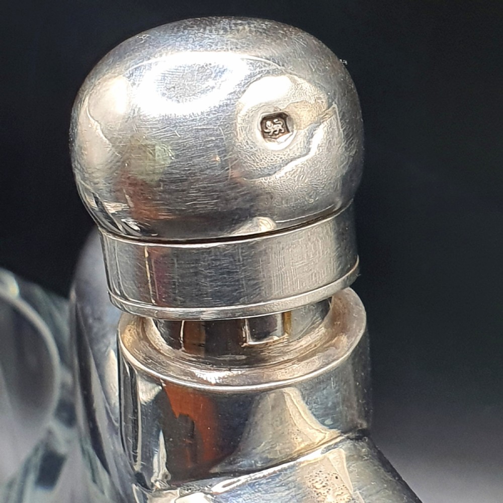 A curved sterling silver hip flask featuring a polished metal surface and a hinged bayonet cap. View III
