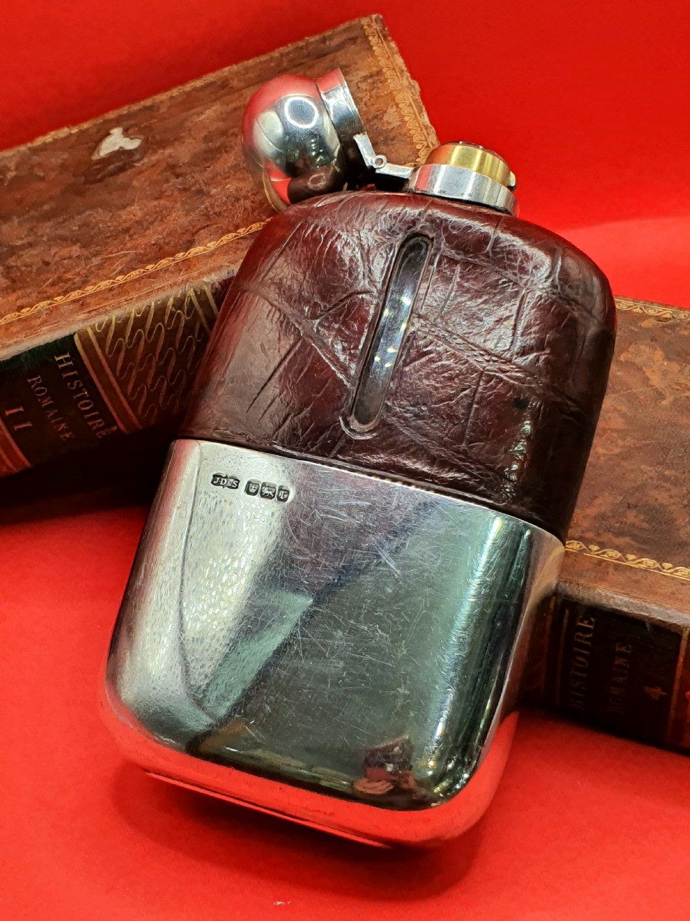 An Edwardian sterling silver hip flask bound in brown crocodile leather featuring a central glass sight window and silver bayonet cap. View V