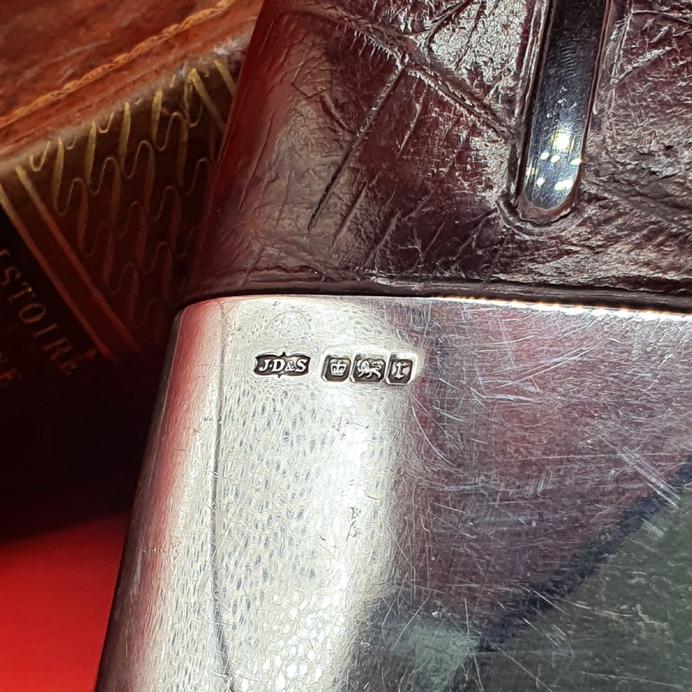 An Edwardian sterling silver hip flask bound in brown crocodile leather featuring a central glass sight window and silver bayonet cap. View VI