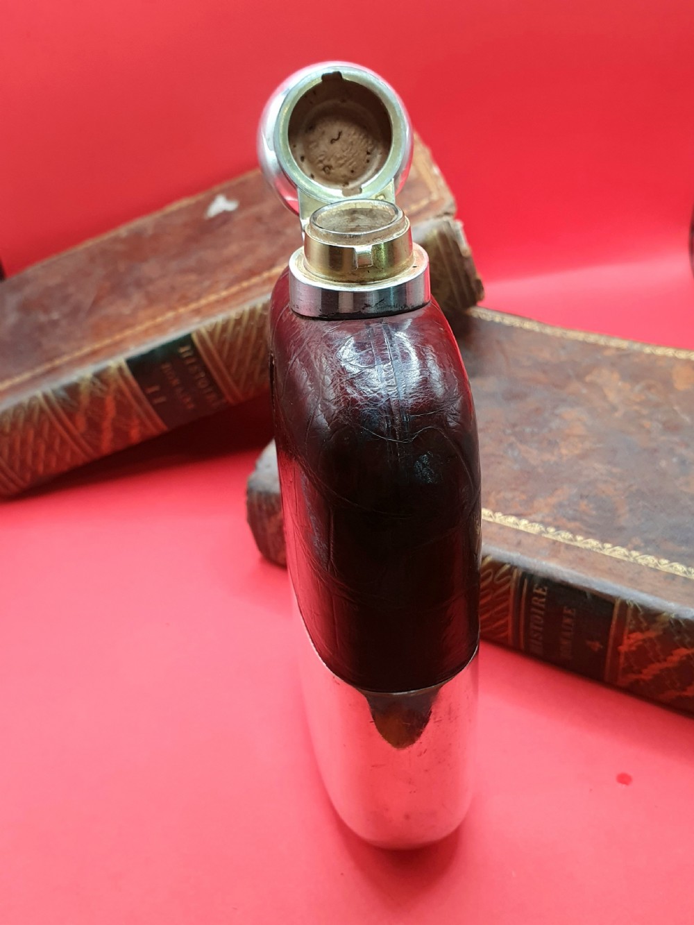 An Edwardian sterling silver hip flask bound in brown crocodile leather featuring a central glass sight window and silver bayonet cap. View IX