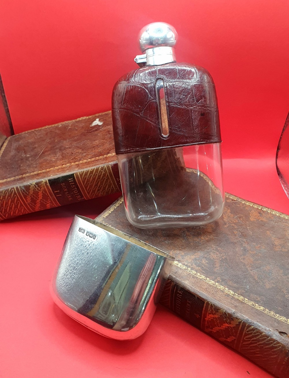 An Edwardian sterling silver hip flask bound in brown crocodile leather featuring a central glass sight window and silver bayonet cap. View X