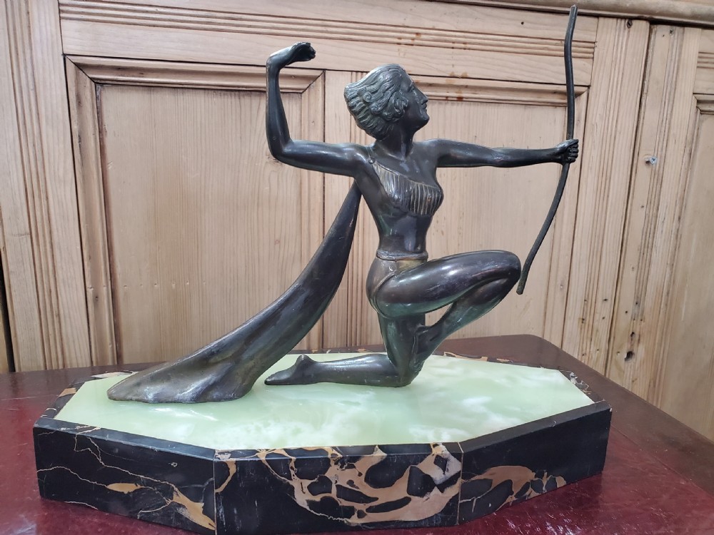 An Art Deco dark metal sculpture depicting Diana the Huntress holding a bow, mounted on a faceted green onyx and black marble base.
