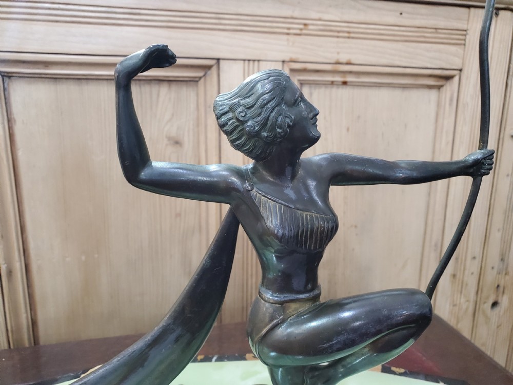 An Art Deco dark metal sculpture depicting Diana the Huntress holding a bow, mounted on a faceted green onyx and black marble base. View II