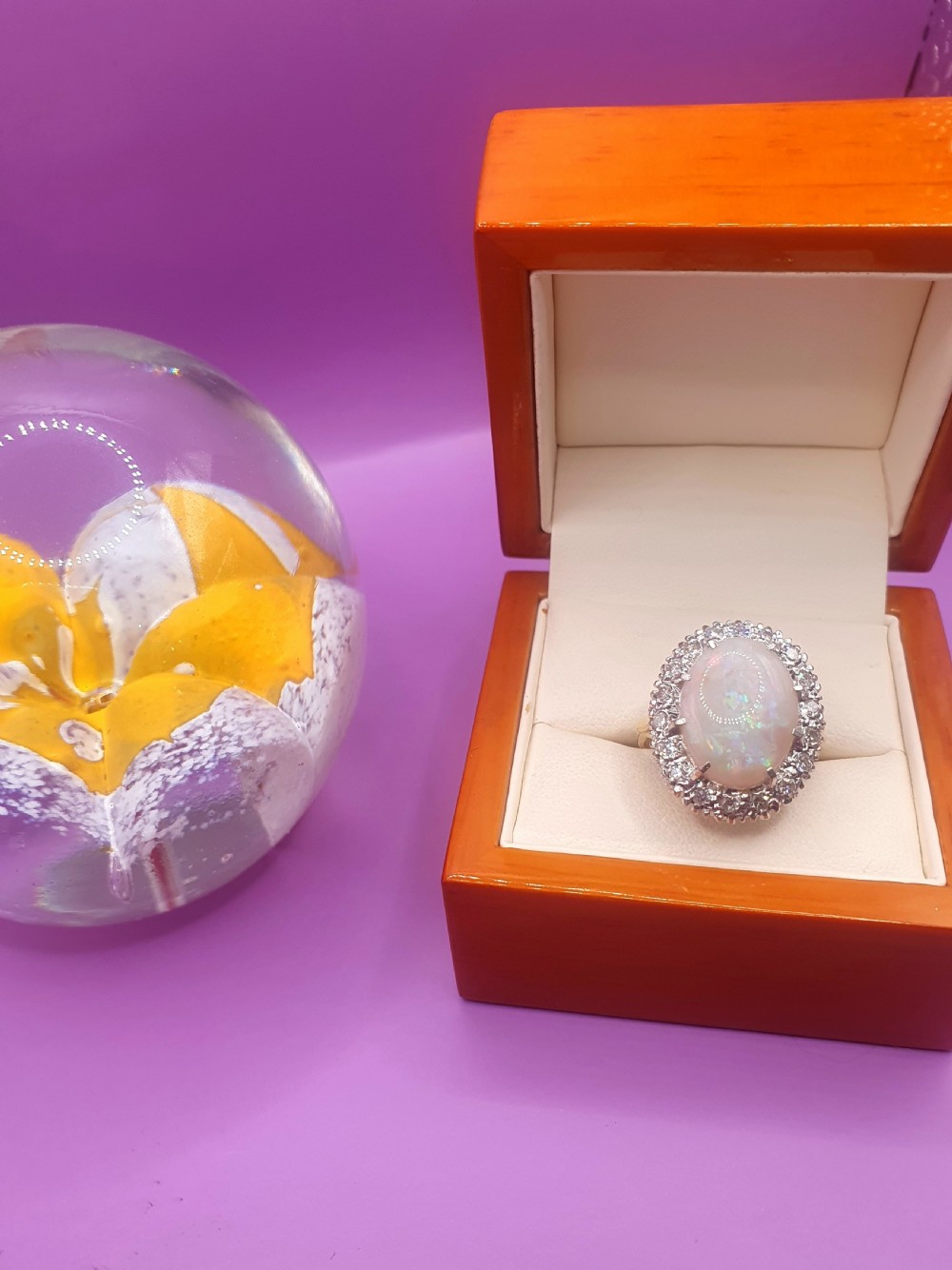 An 18ct gold ring featuring a central oval cabochon opal surrounded by a halo of small diamonds. View II