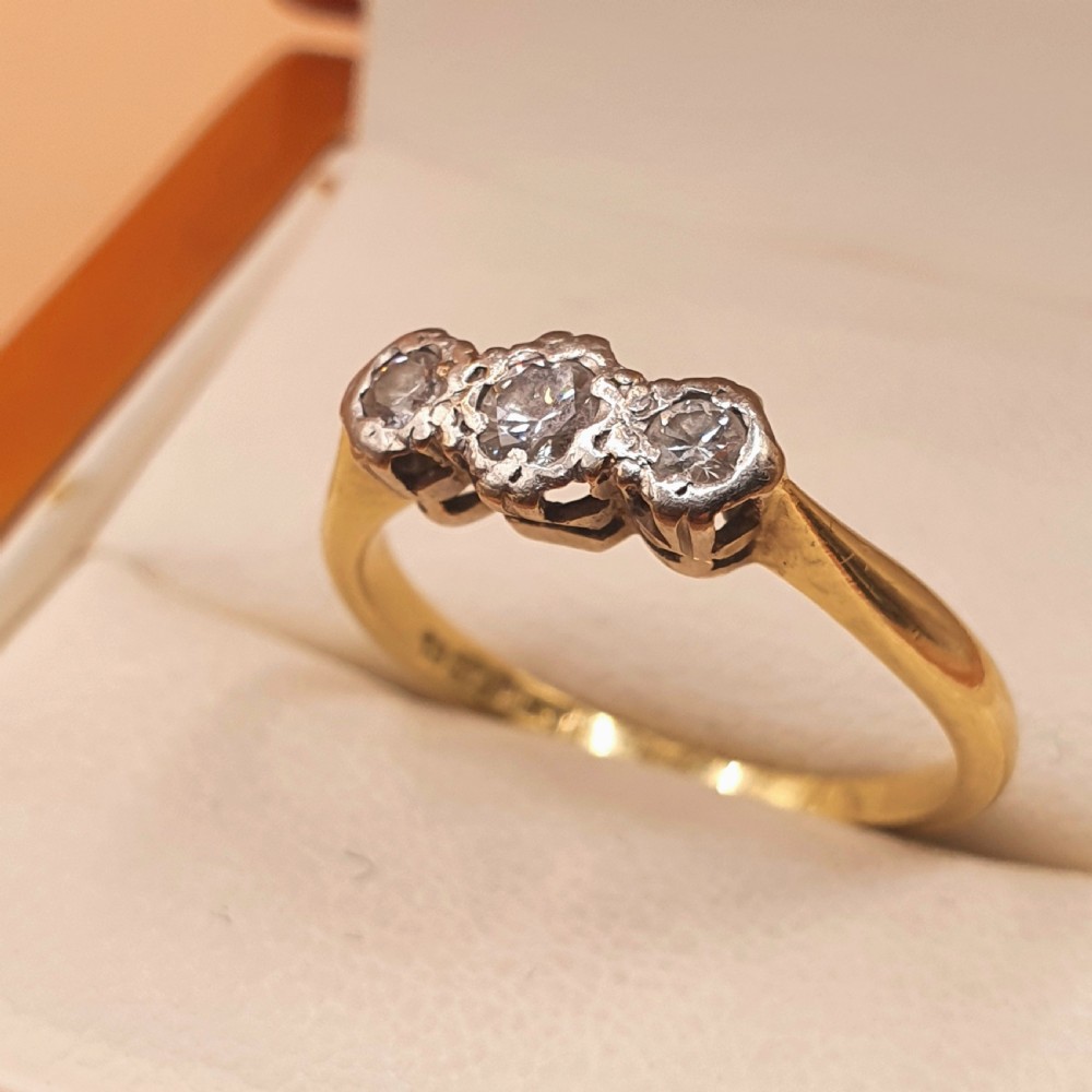 An Art Deco trilogy ring featuring three round diamonds set in a platinum mount on an 18ct yellow gold band. View II