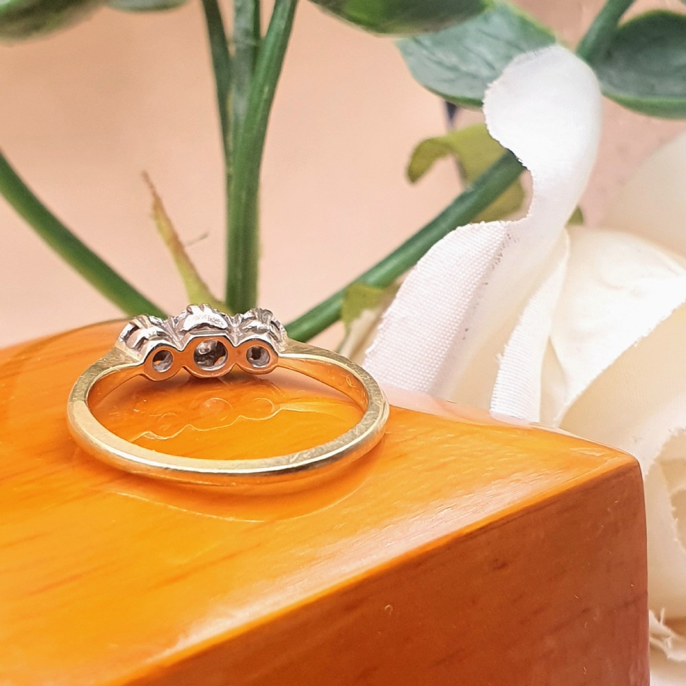 An Art Deco trilogy ring featuring three round diamonds set in a platinum mount on an 18ct yellow gold band. View VII