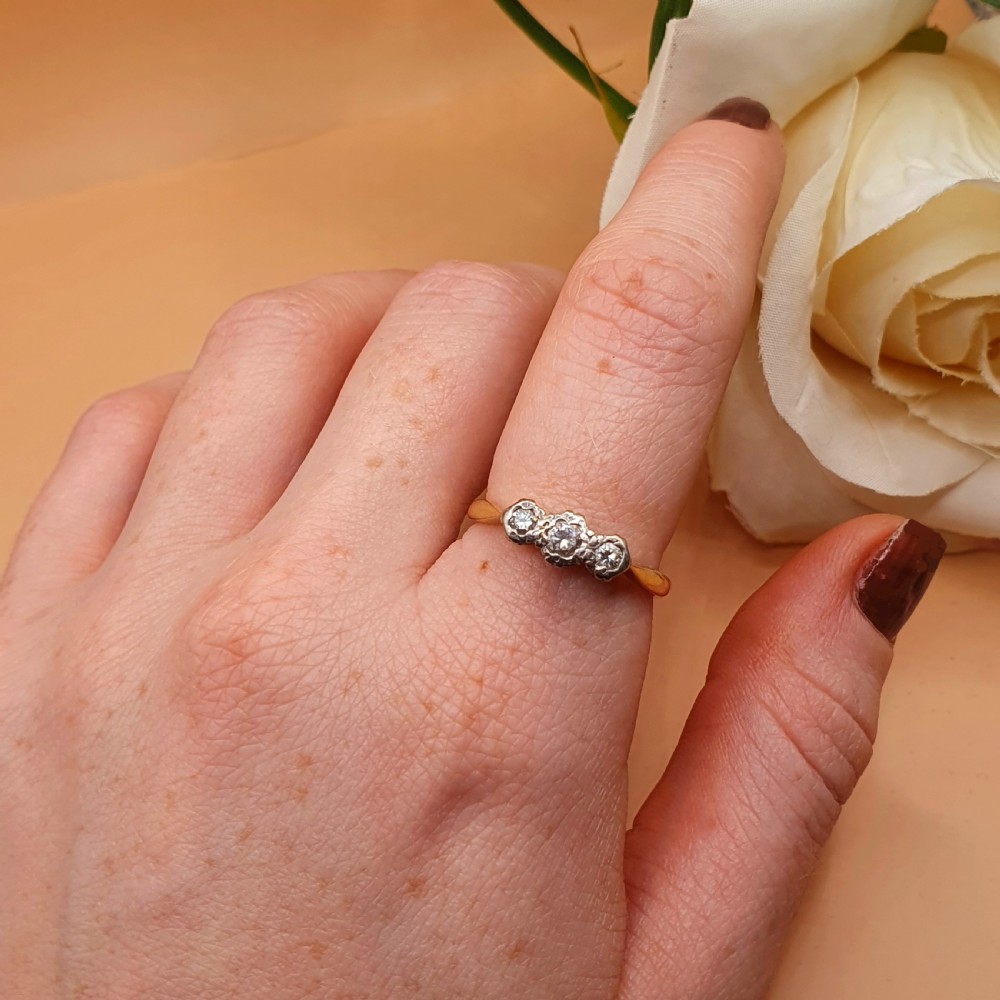 An Art Deco trilogy ring featuring three round diamonds set in a platinum mount on an 18ct yellow gold band. View VIII