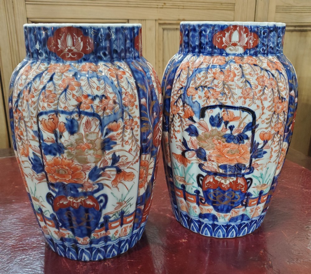 A pair of 19th-century Japanese Imari porcelain fluted vases decorated in cobalt blue, iron-red, and gold floral patterns.