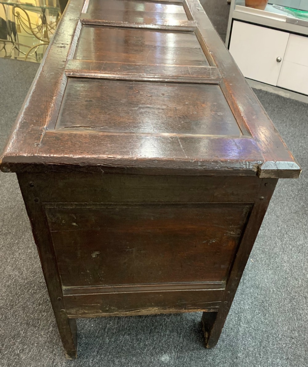 An 18th-century dark oak coffer featuring a three-panel hinged top, carved frieze rail, iron lock plate, and raised stile feet. View VIII
