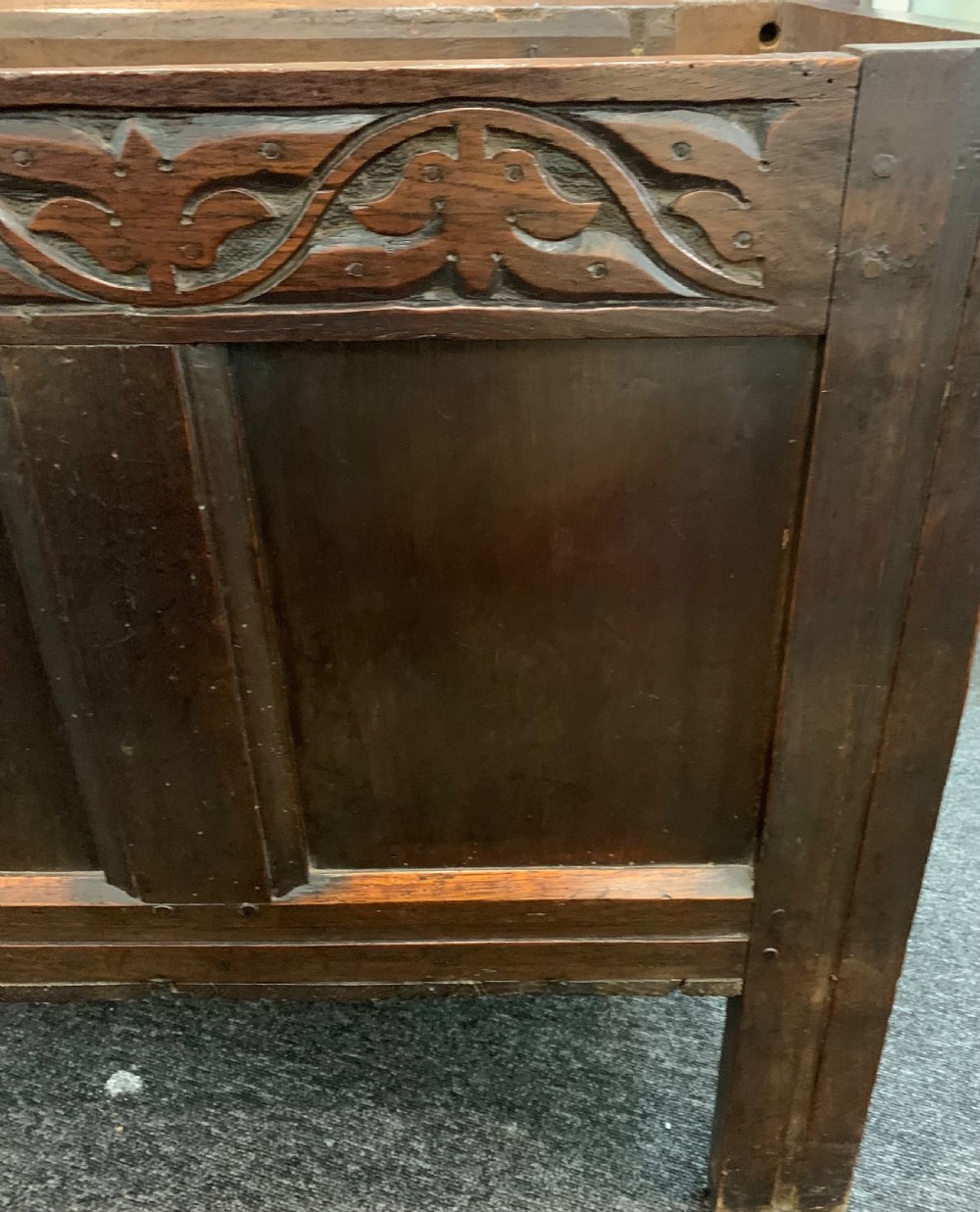 An 18th-century dark oak coffer featuring a three-panel hinged top, carved frieze rail, iron lock plate, and raised stile feet. View IX