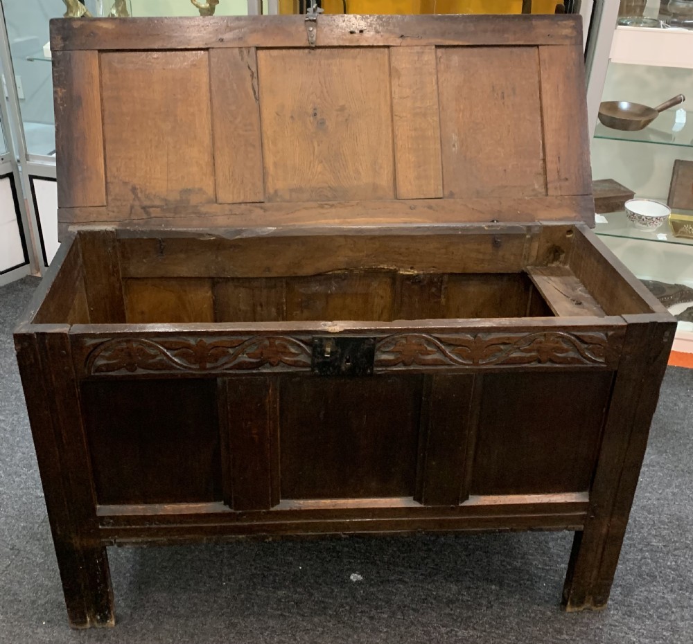 An 18th-century dark oak coffer featuring a three-panel hinged top, carved frieze rail, iron lock plate, and raised stile feet. View XI