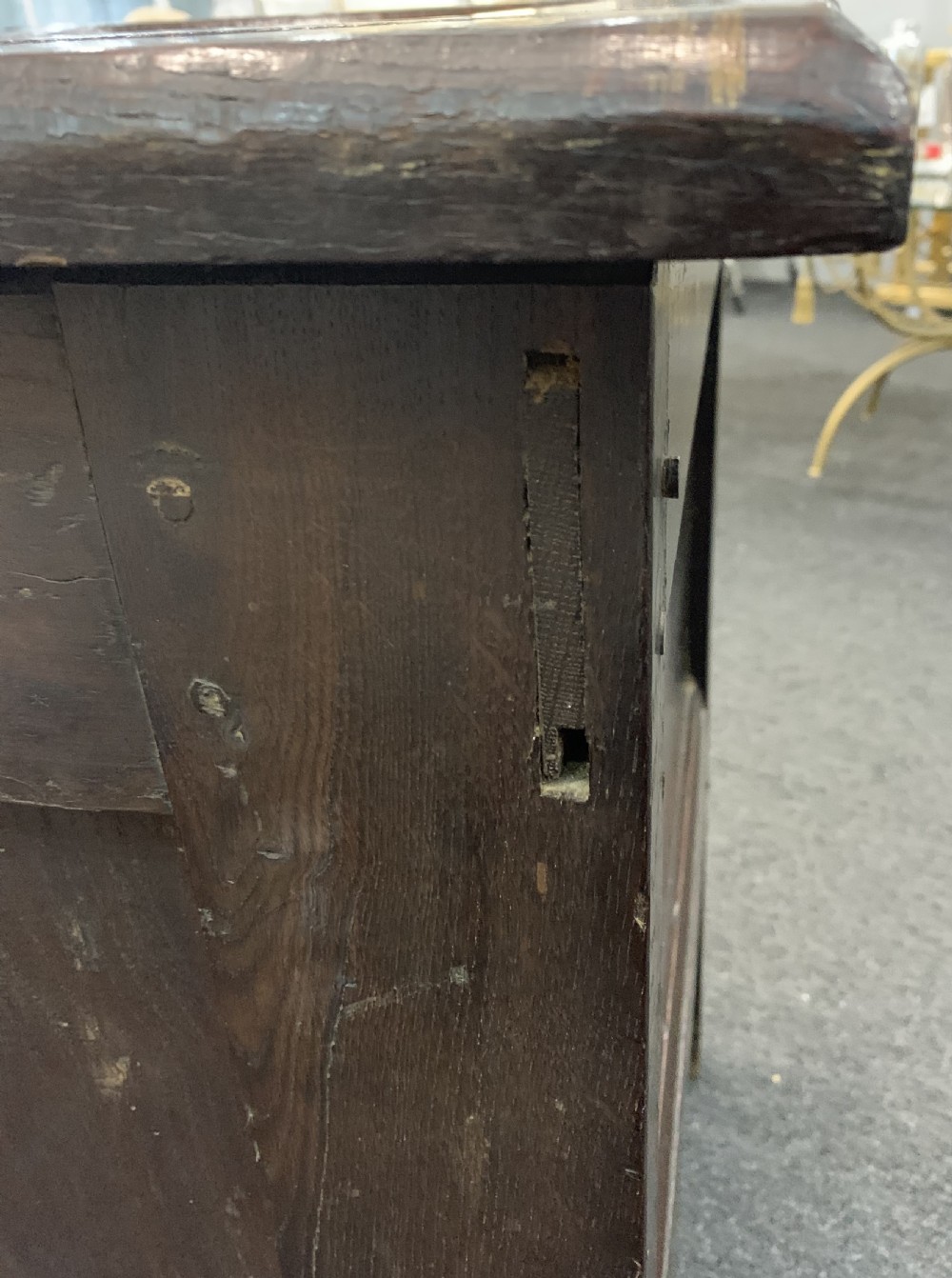 An 18th-century dark oak coffer featuring a three-panel hinged top, carved frieze rail, iron lock plate, and raised stile feet. View XIII