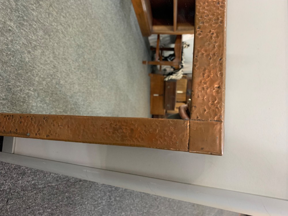A rectangular wall mirror featuring a wide hand-hammered copper frame with a textured finish. View V