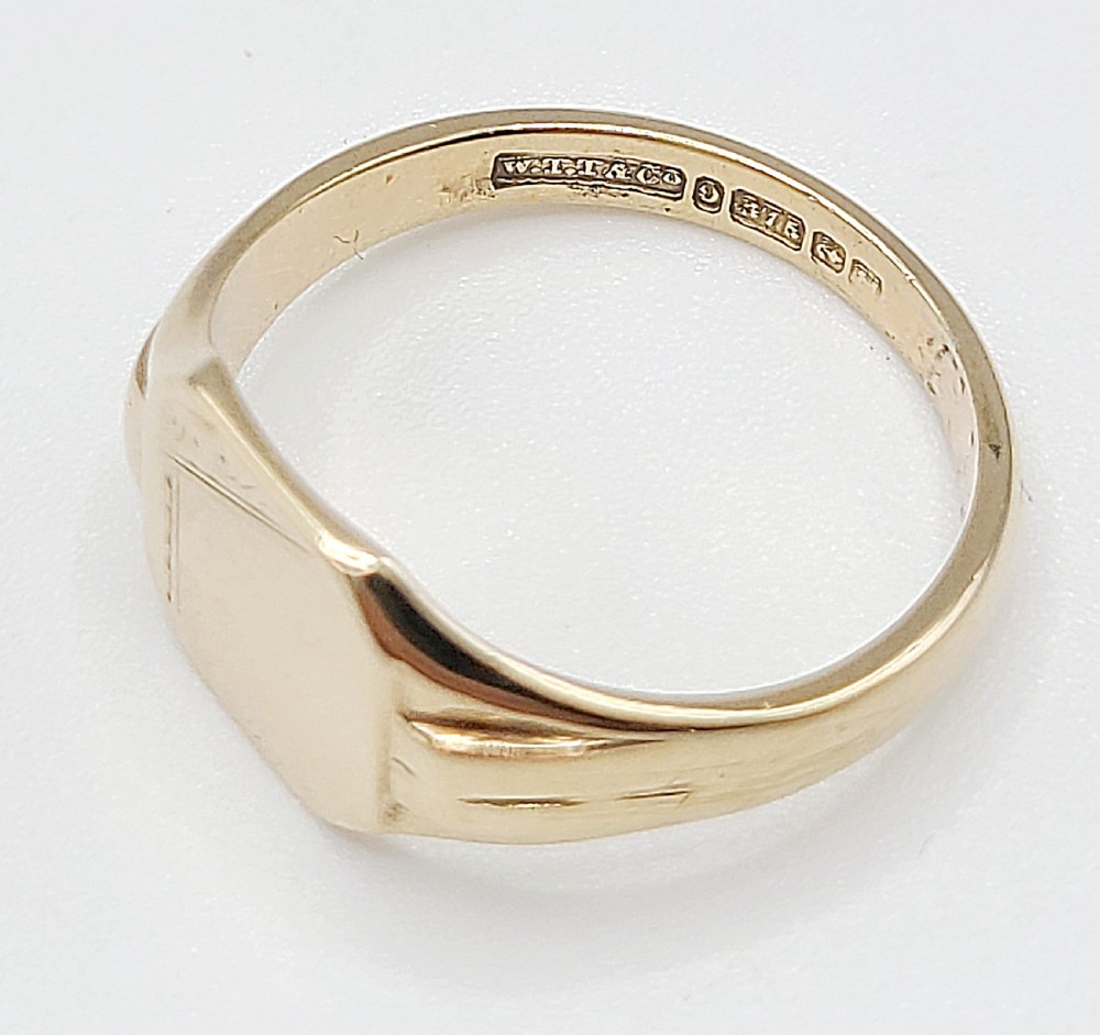 An Art Deco 9ct yellow gold signet ring featuring a flat hexagonal bezel with linear engraved details on the top edge and shoulders. View VI
