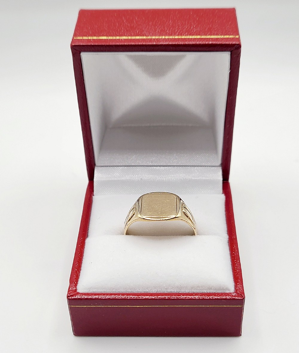 A vintage 9ct yellow gold signet ring featuring a flat cushion-shaped bezel and grooved details on the shoulders. View III