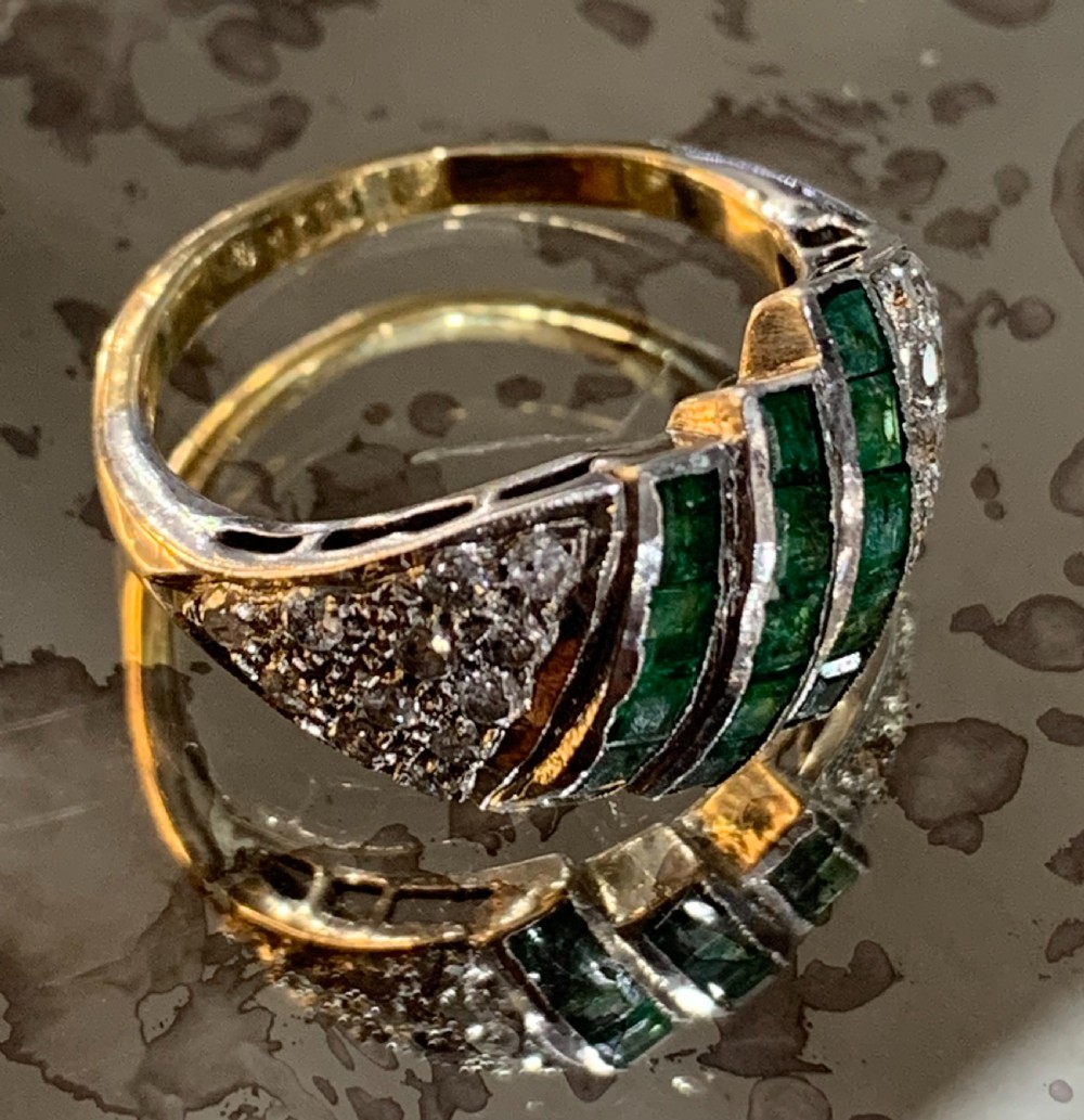 An Art Deco 18ct yellow and white gold cluster ring featuring diagonal rows of square green emeralds flanked by pave-set diamonds. View VII