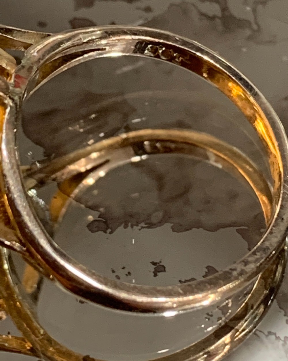 An Art Deco period 9ct gold solitaire ring featuring a large faceted orange synthetic sapphire held in claw settings. View IV