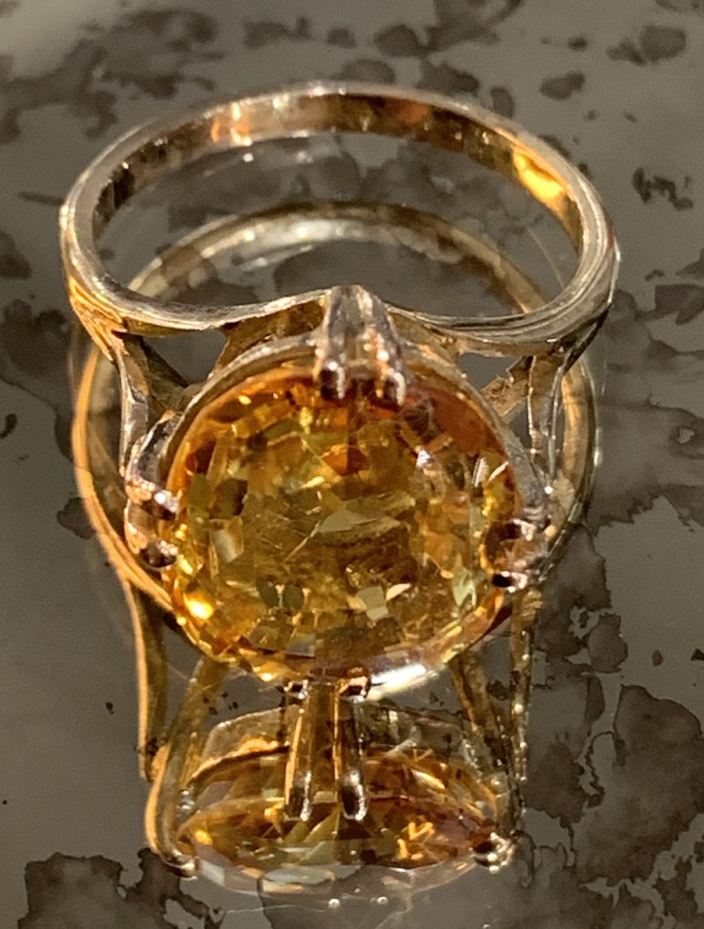 An Art Deco period 9ct gold solitaire ring featuring a large faceted orange synthetic sapphire held in claw settings. View VI