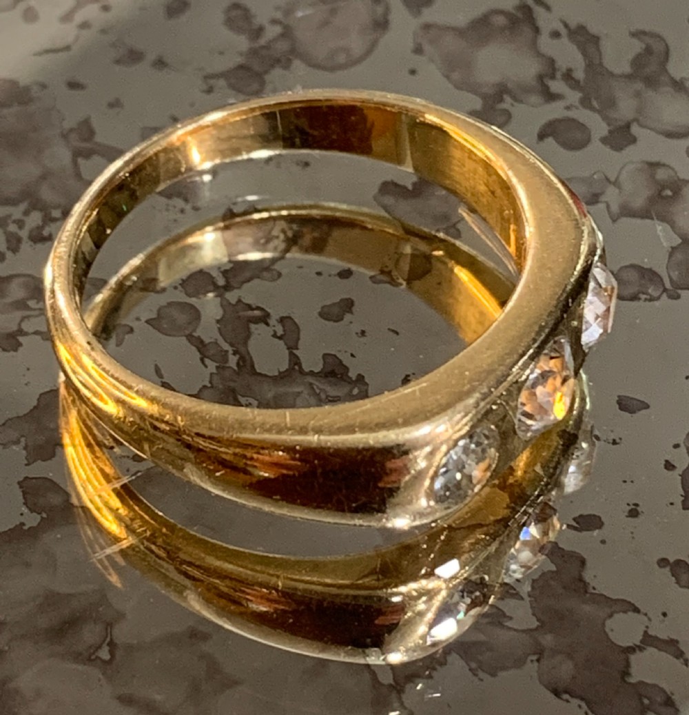 A solid 18ct yellow gold band ring featuring three flush-set round diamonds across the top profile. View III
