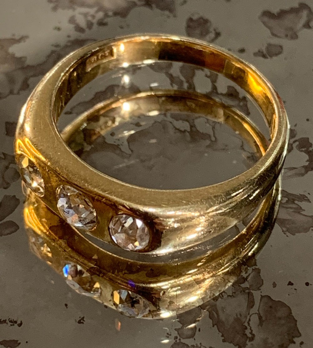 A solid 18ct yellow gold band ring featuring three flush-set round diamonds across the top profile.
