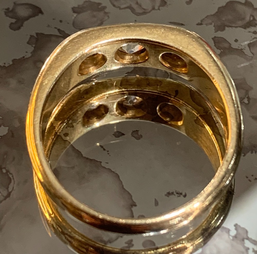 A solid 18ct yellow gold band ring featuring three flush-set round diamonds across the top profile. View VI
