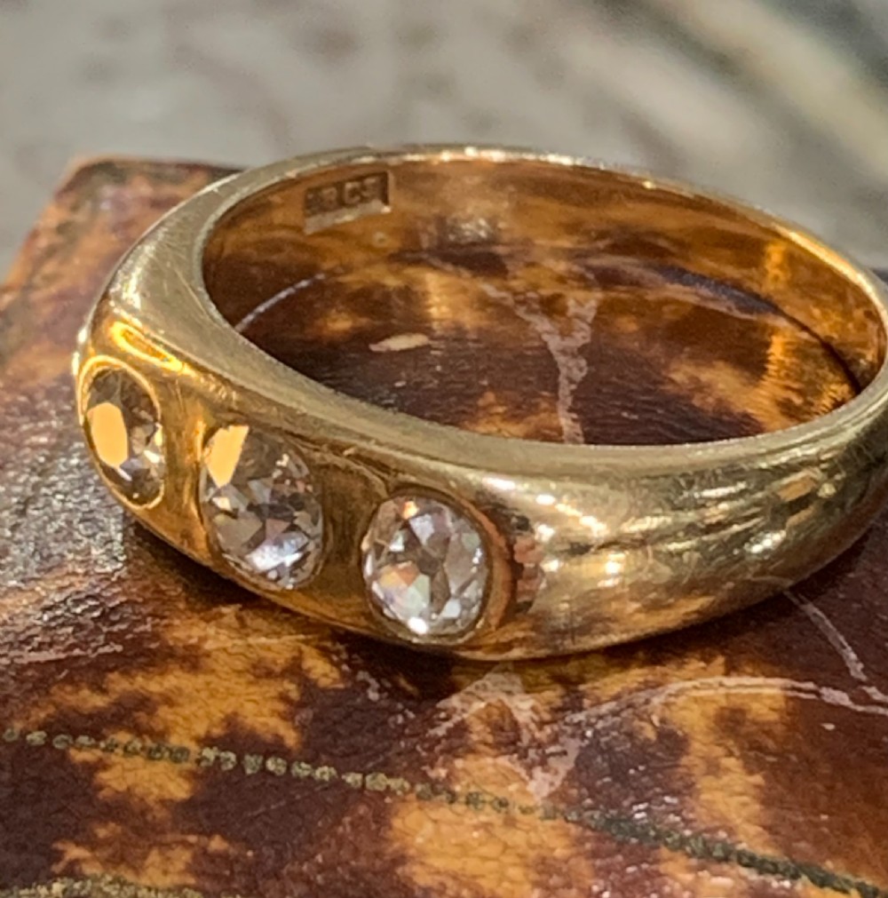 A solid 18ct yellow gold band ring featuring three flush-set round diamonds across the top profile. View VII