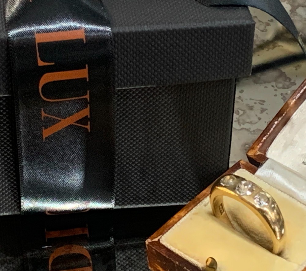 A solid 18ct yellow gold band ring featuring three flush-set round diamonds across the top profile. View VIII