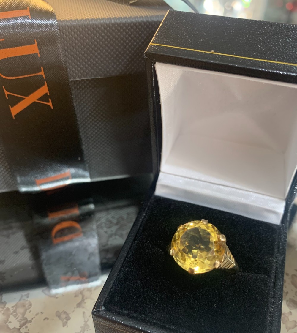 An Art Deco 9ct yellow gold solitaire ring featuring a large round old-cut yellow citrine gemstone held in a multi-claw setting with stepped shoulders. View IV