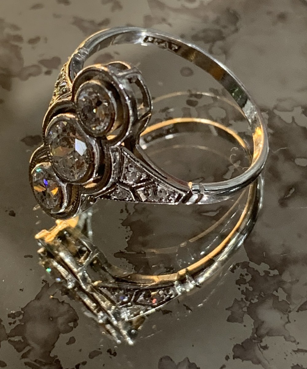 An antique Art Deco platinum ring featuring three vertically aligned old-cut diamonds with intricate millegrain detailing. View II