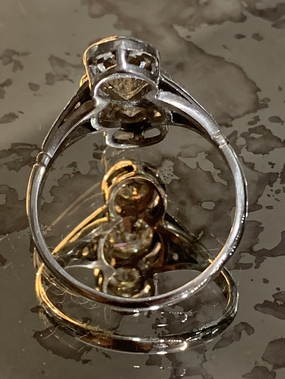 An antique Art Deco platinum ring featuring three vertically aligned old-cut diamonds with intricate millegrain detailing. View III