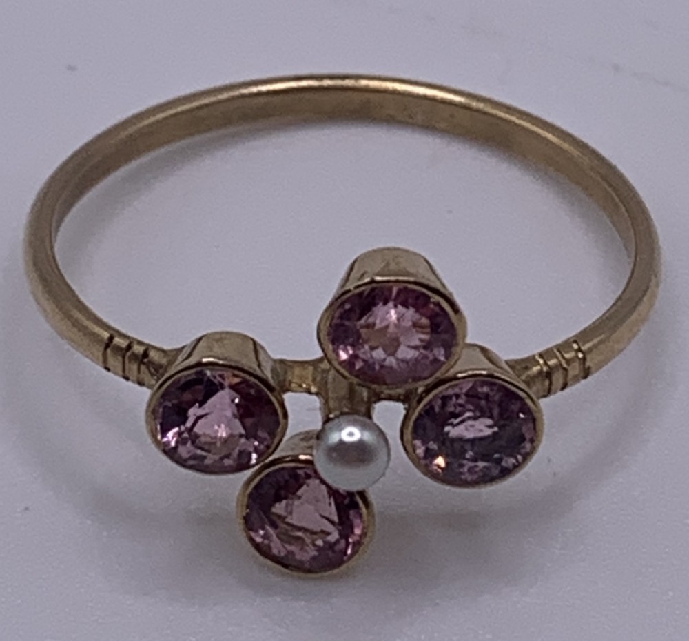 A Victorian 15ct gold ring featuring four circular pink tourmalines bezel-set around a central seed pearl.