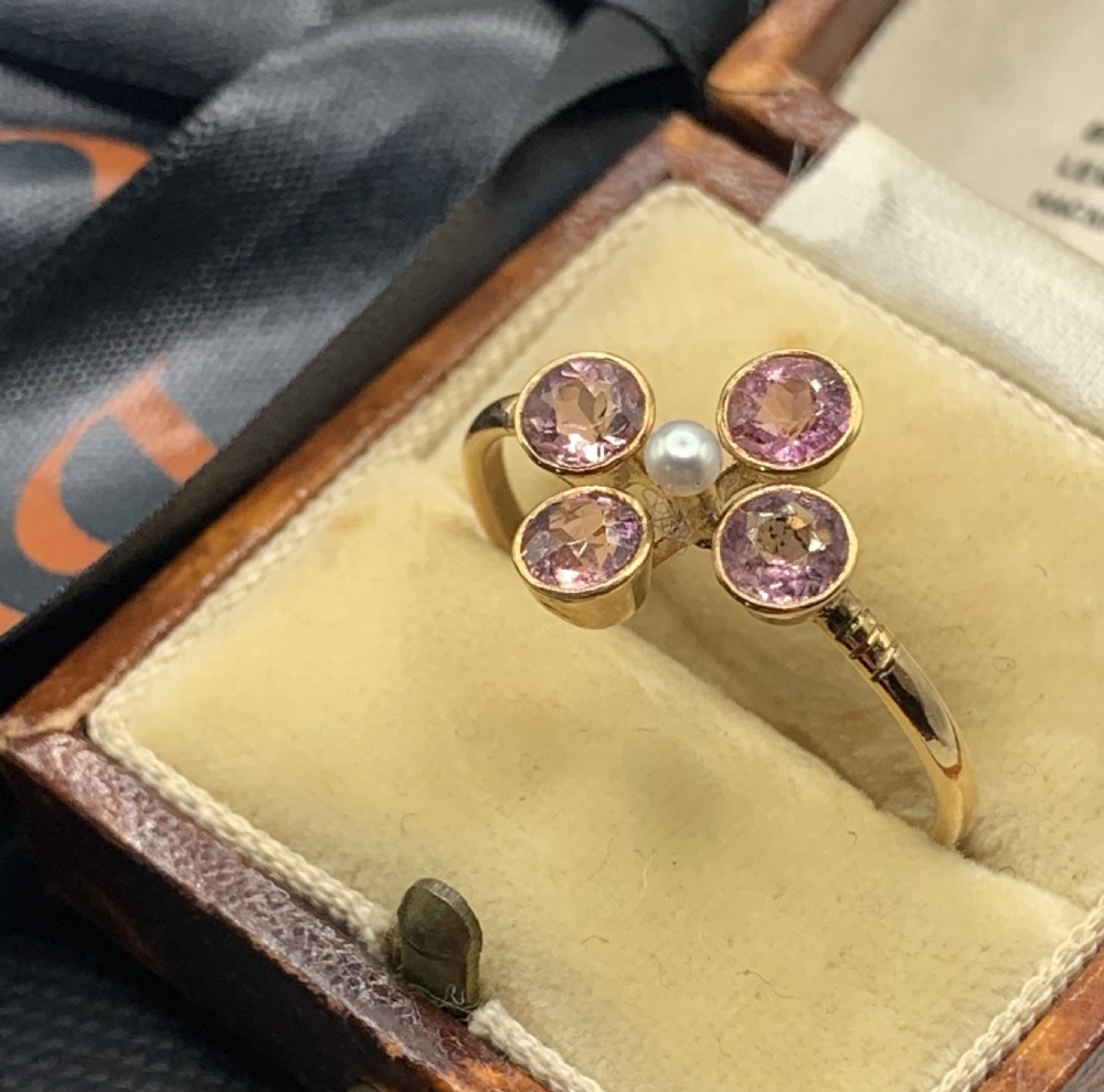 A Victorian 15ct gold ring featuring four circular pink tourmalines bezel-set around a central seed pearl. View VI