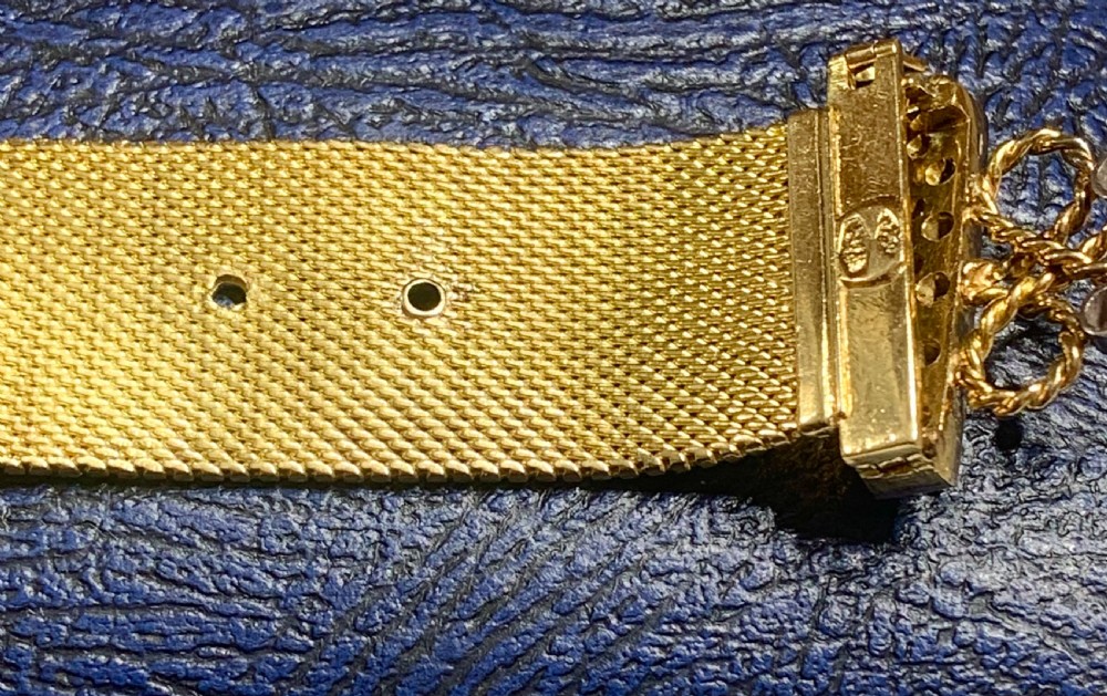 An Art Deco 18ct yellow gold mesh band bracelet featuring a diamond-set vertical bar, wire scrollwork, and a hanging gold tassel fringe. View IV