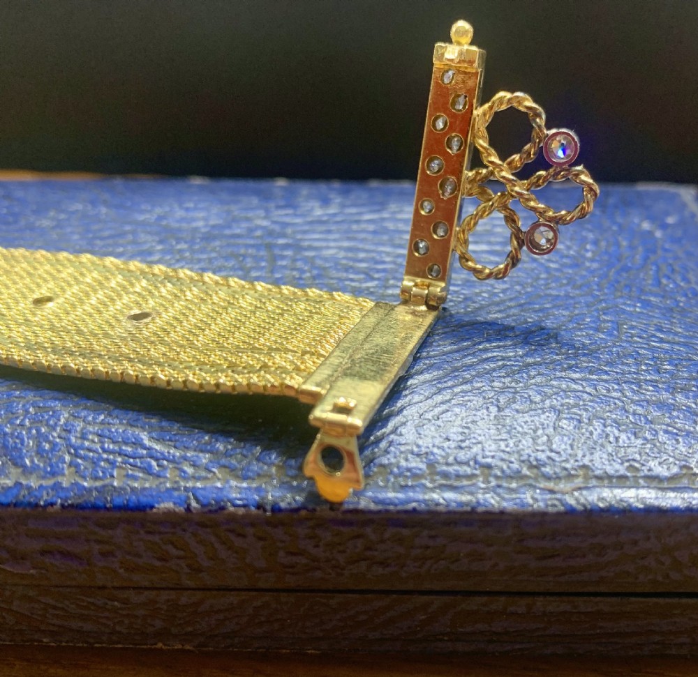 An Art Deco 18ct yellow gold mesh band bracelet featuring a diamond-set vertical bar, wire scrollwork, and a hanging gold tassel fringe. View VI