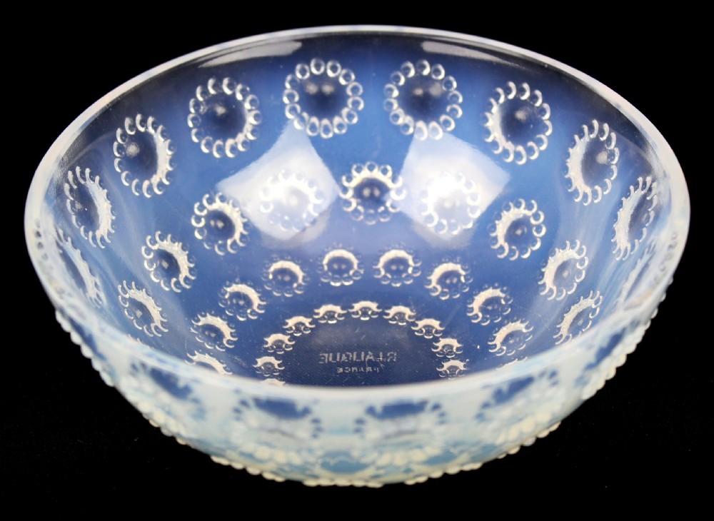 A circular Art Deco opalescent glass bowl featuring concentric moulded aster flower head motifs against a translucent light blue hue. View II