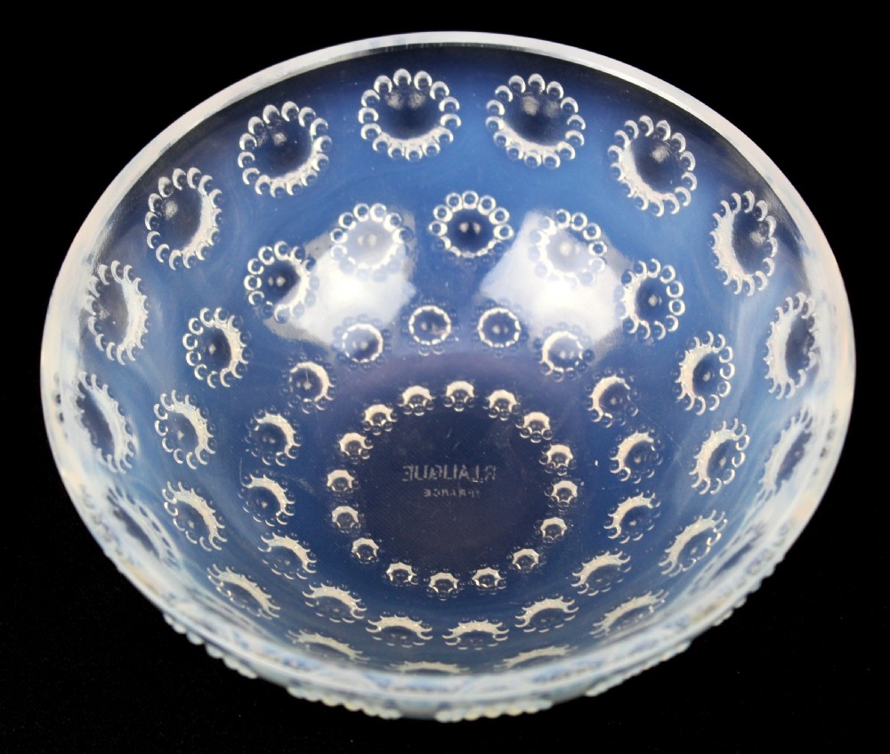 A circular Art Deco opalescent glass bowl featuring concentric moulded aster flower head motifs against a translucent light blue hue. View III