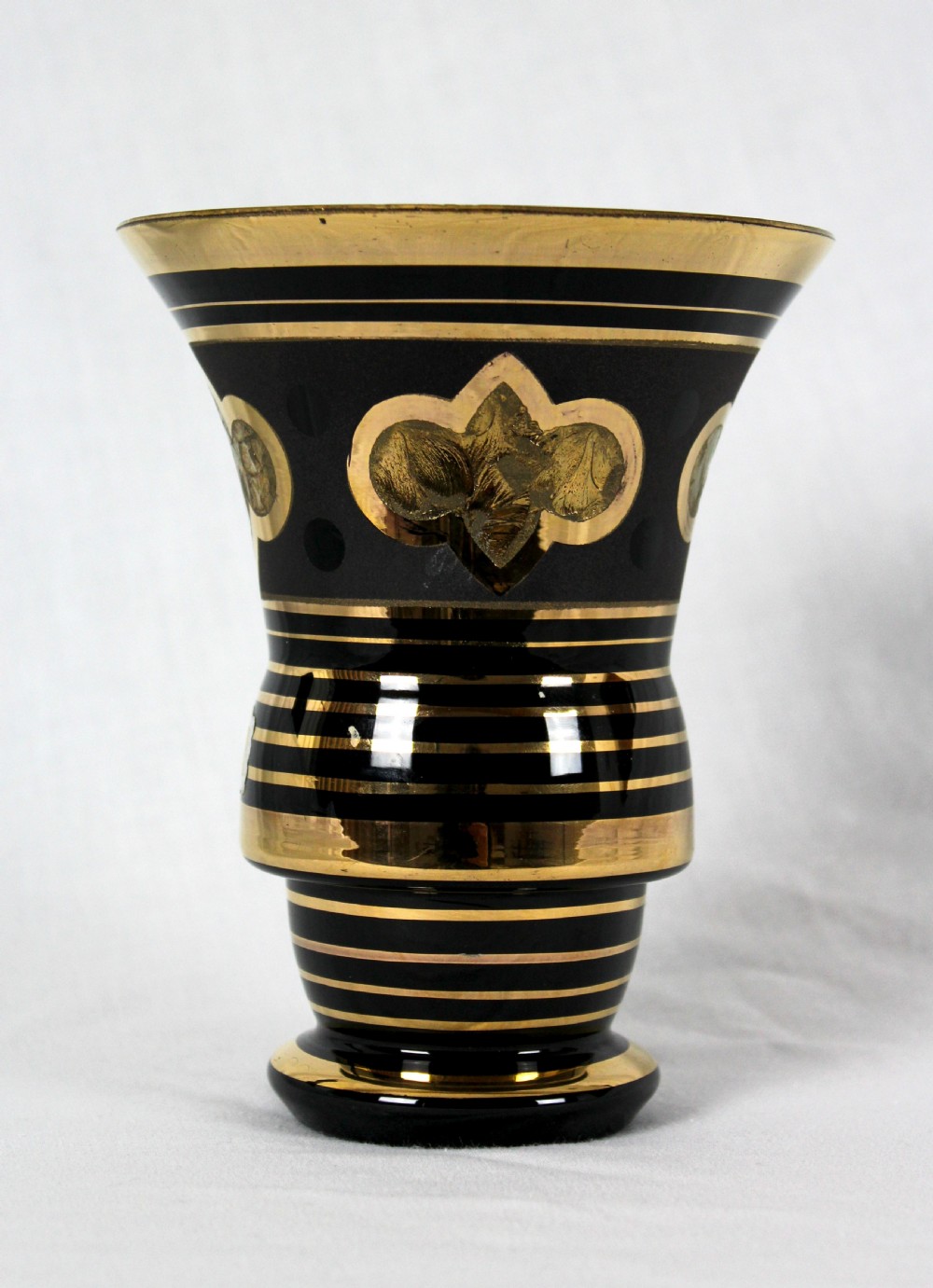 An Art Deco black hyalite glass vase featuring horizontal gold bands and stylized floral medallions.
