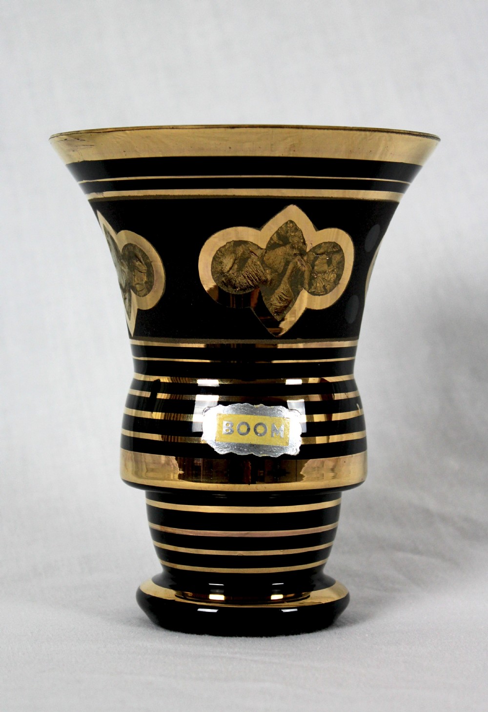 An Art Deco black hyalite glass vase featuring horizontal gold bands and stylized floral medallions. View II