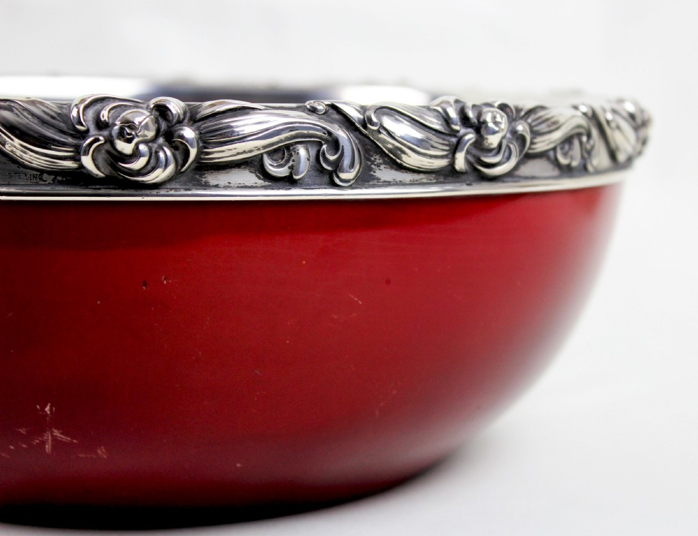 A deep circular red flambe ceramic bowl featuring a thick repousse sterling silver rim with floral and scroll reliefs. View III