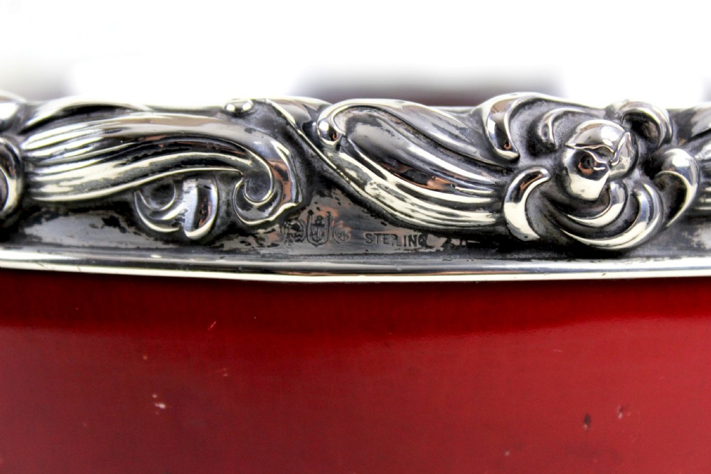 A deep circular red flambe ceramic bowl featuring a thick repousse sterling silver rim with floral and scroll reliefs. View VI