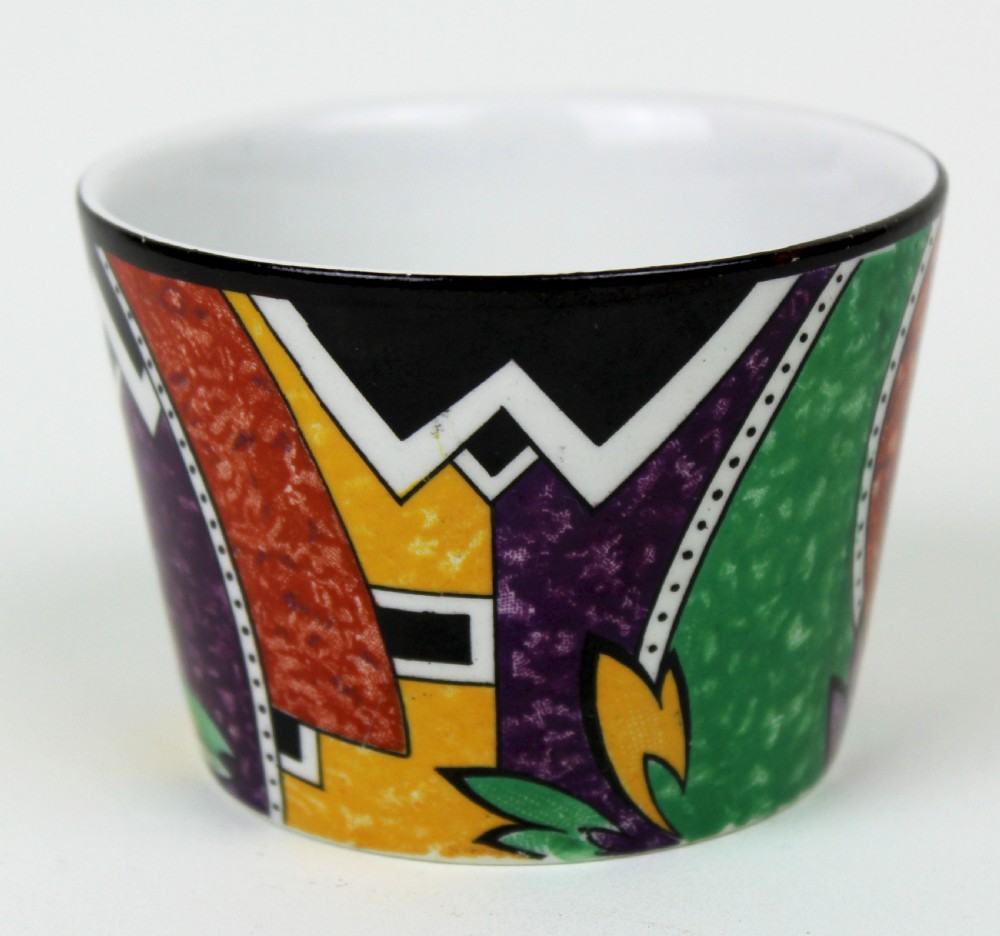 A multi-piece Art Deco ceramic coffee set decorated with vibrant red, yellow, green, and black abstract geometric patterns, comprising a tall coffee pot, creamer, sugar bowl, six demitasse cups, and matching saucers. View III
