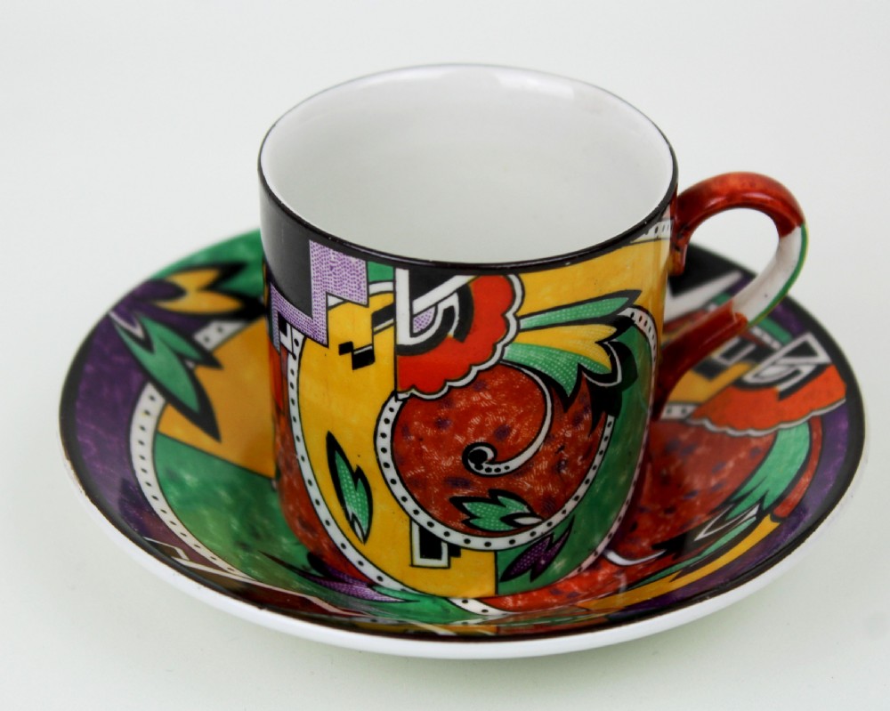 A multi-piece Art Deco ceramic coffee set decorated with vibrant red, yellow, green, and black abstract geometric patterns, comprising a tall coffee pot, creamer, sugar bowl, six demitasse cups, and matching saucers. View V