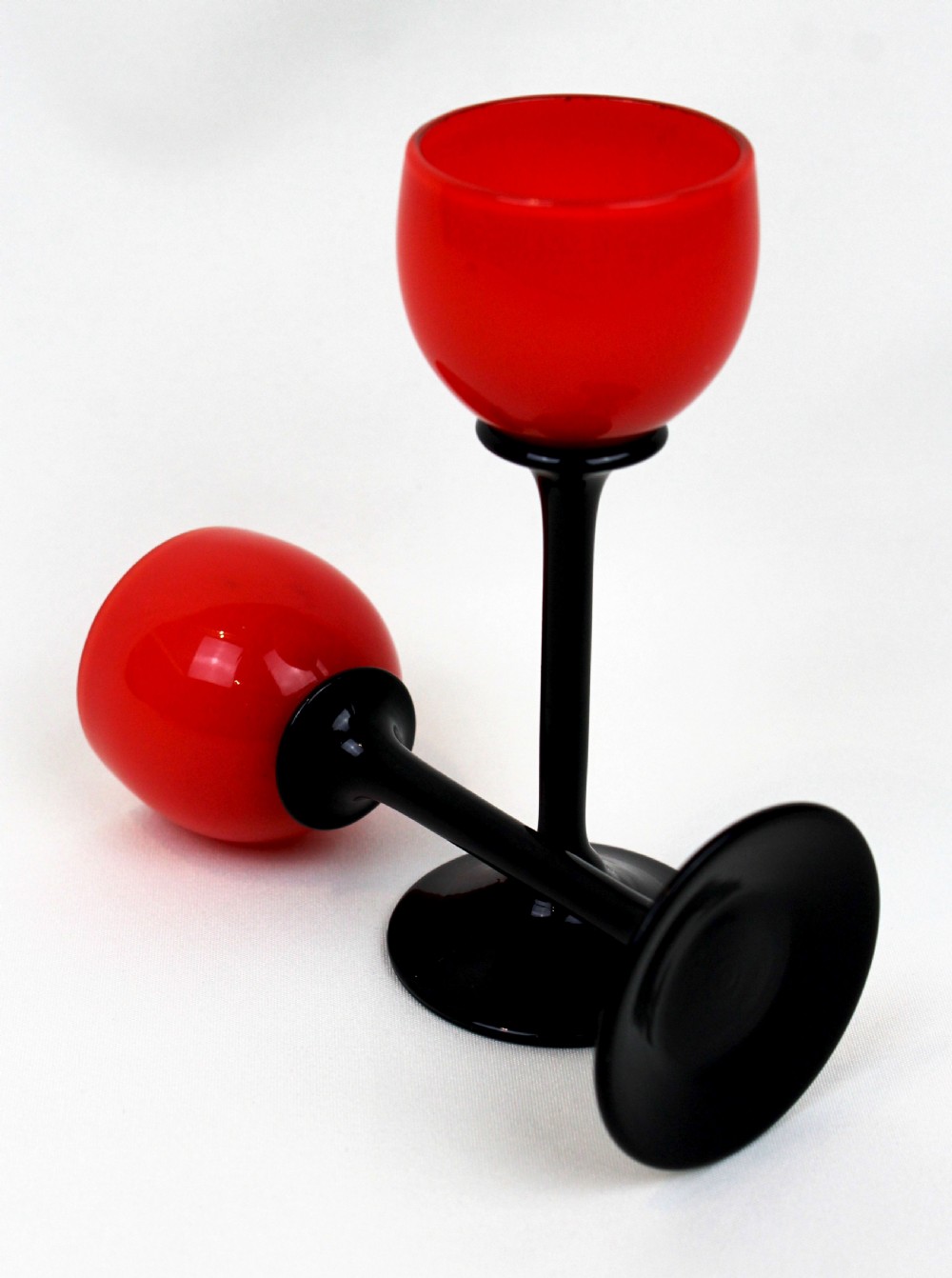 A pair of Art Deco Tango liqueur glasses featuring bright red rounded bowls supported by slender black stems and flat circular black bases. View II